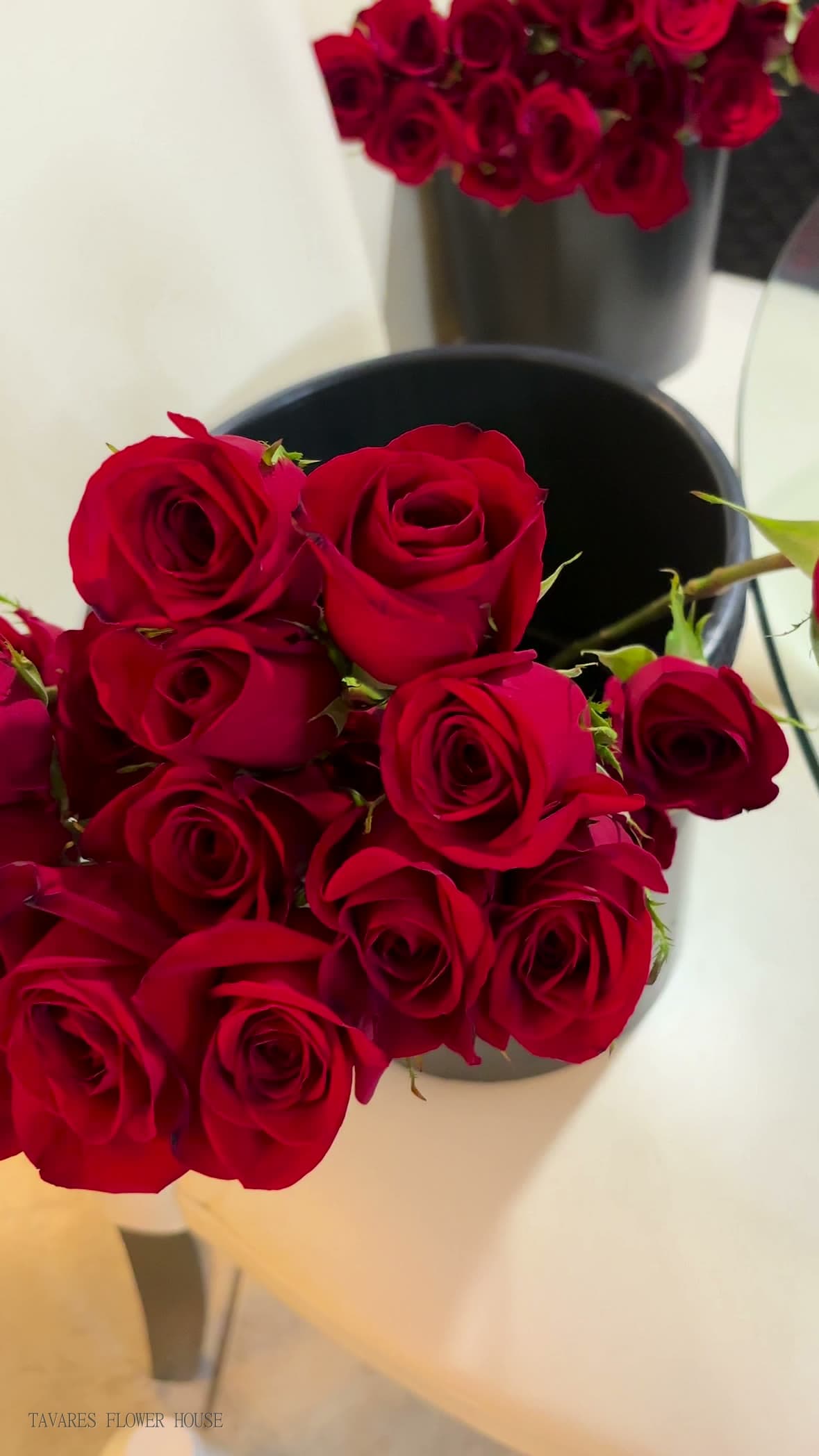 Deep red roses resting in a black bucket while they are conditioned before arranging