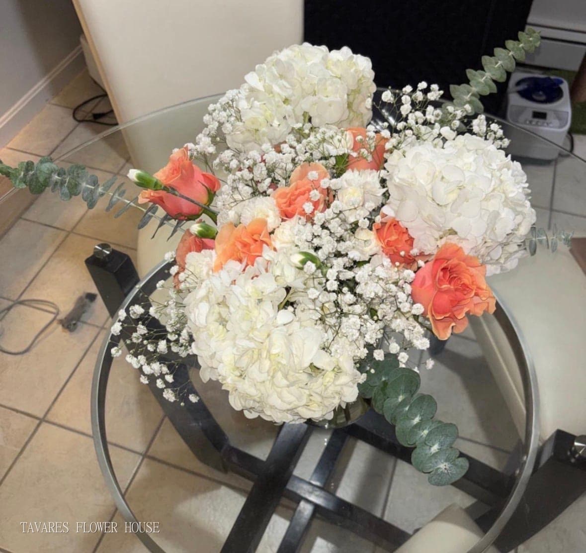 Sympathy arrangement of white hydrangeas, coral roses, white carnations, baby’s breath and eucalyptus
